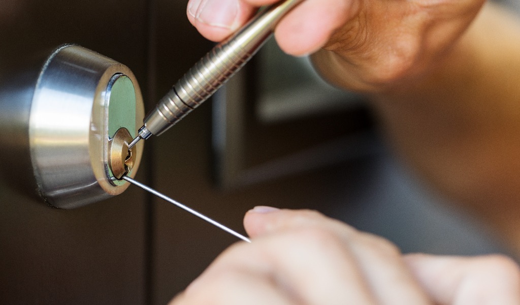Closeup of locksmith hands using pick tools to open locked door jpg